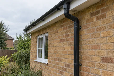 Gutter outlet and downpipe on a brick wall