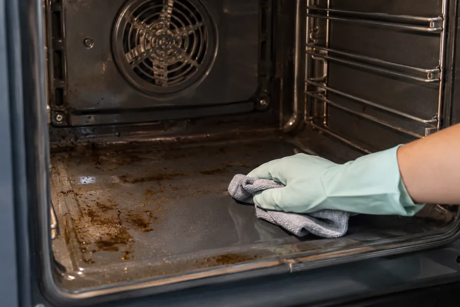 Cloth wiping baked grease inside an oven with intact fan cover