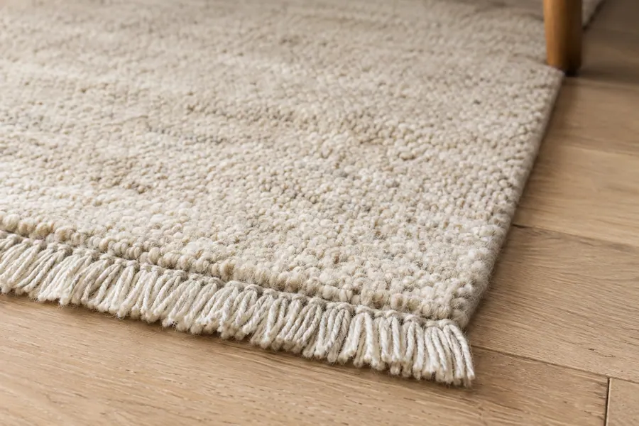 Wool rug fibres and short plain fringe at an edge